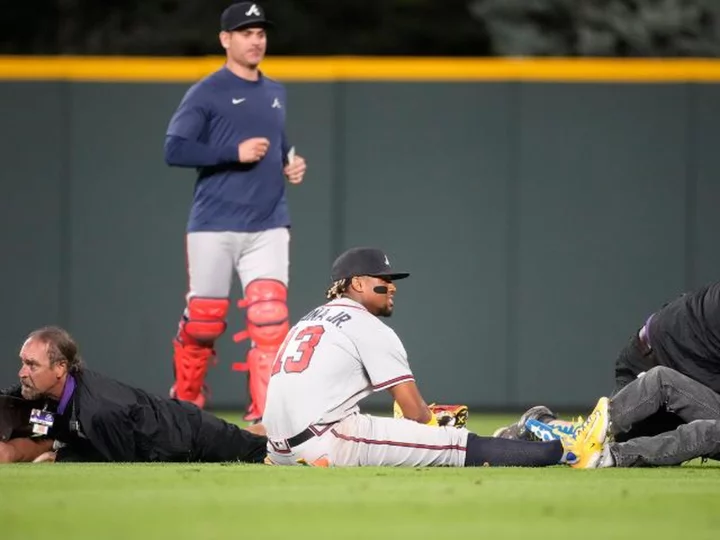 Atlanta Braves' Ronald Acuña Jr. knocked to the ground after two fans run onto Coors Field