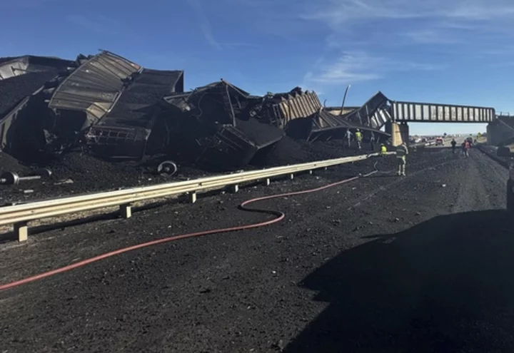 Colorado train derails, spilling train cars and coal onto a highway and trapping a semi-truck driver